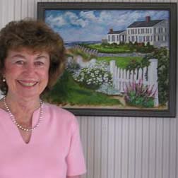 A woman in a pink shirt standing in front of a painting.