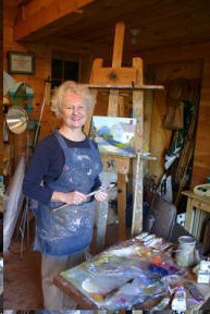 A woman standing in front of an easel in an art studio.