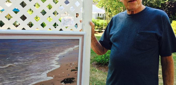 A man standing next to a framed painting.