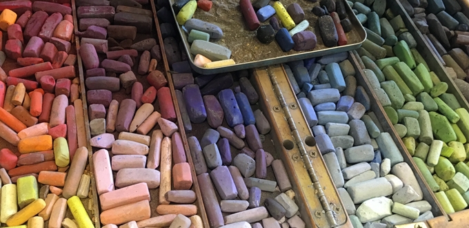 A tray of colored chalks on a table.