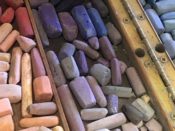 A pile of colored chalks in a wooden box.