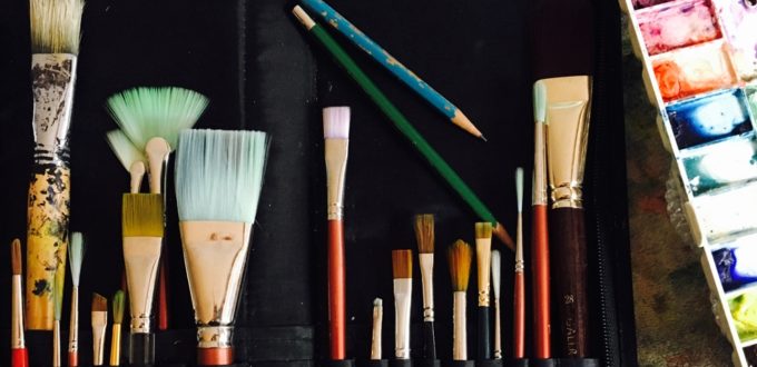 A set of paint brushes and palettes on a table.