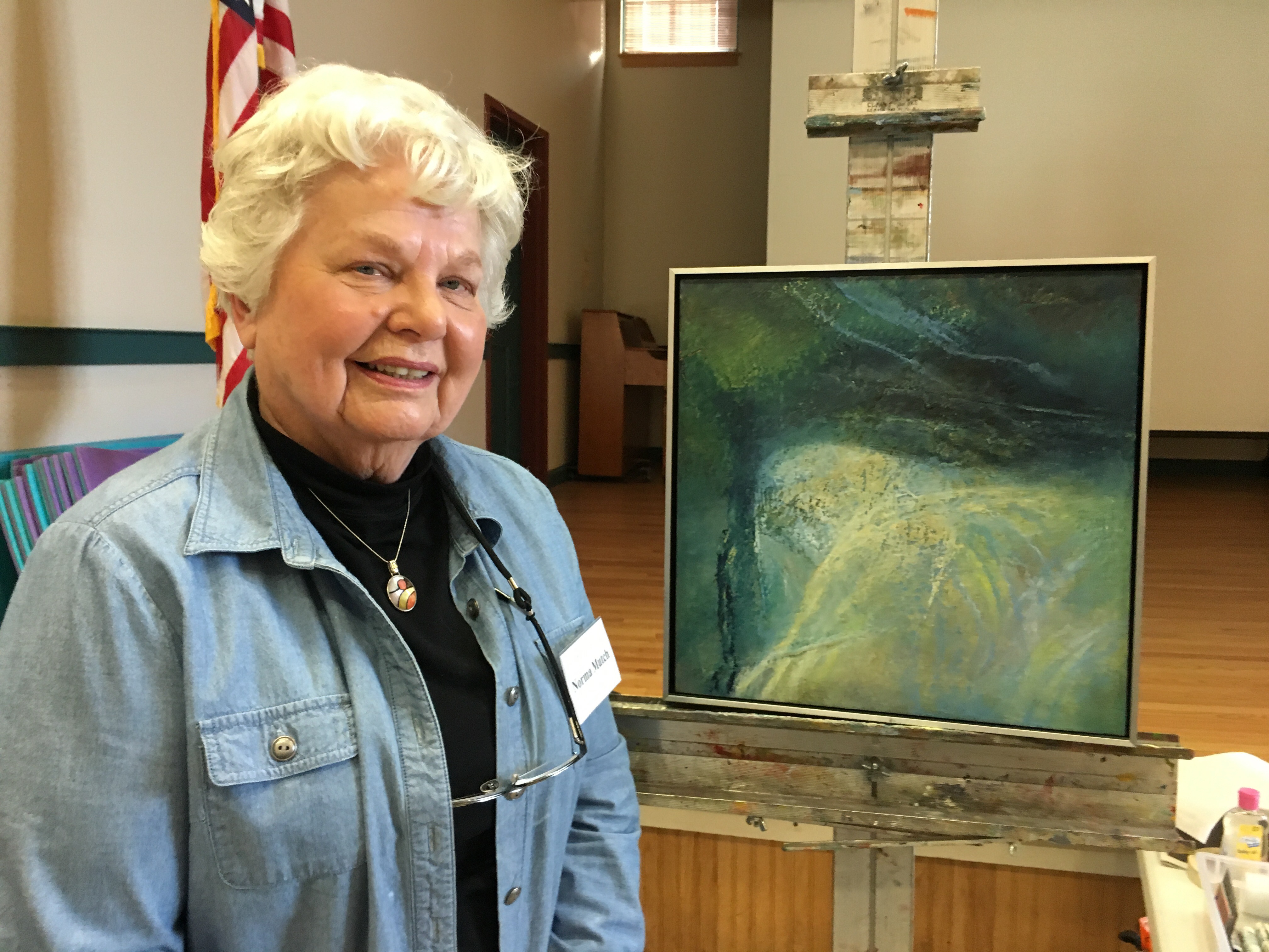An older woman standing in front of a painting.
