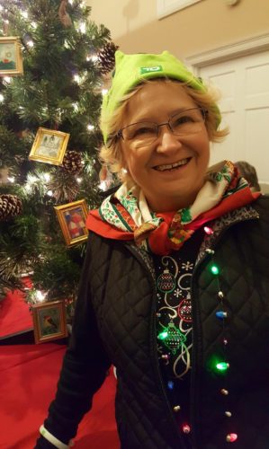 A woman standing in front of a christmas tree.