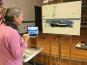 A woman is painting a boat on an easel.