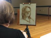 A woman painting a picture on a easel.