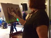 A woman painting a portrait on an easel.