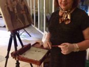 A woman standing next to an easel painting a portrait.