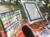 An easel with paints on it in a park.