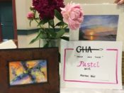 A table with flowers and a sign that says gha pastel art show.