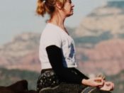 A woman sitting on a rock and meditating.