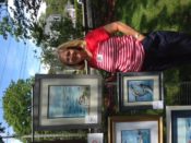 A woman standing next to two framed paintings.