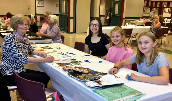 The Guild of Harwich Artists hosted a successful community art event, with a group of girls sitting at a table with books.