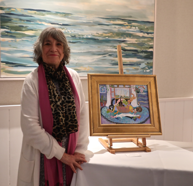 A woman standing beside a table with a painting