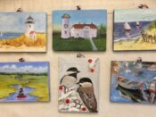 A group of paintings of birds and lighthouses hanging on a wall.