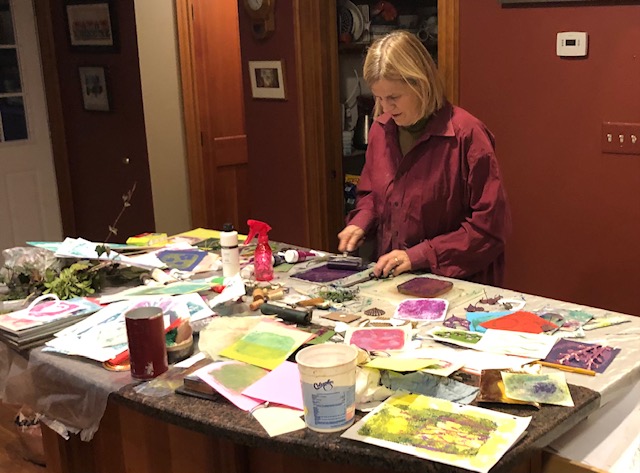 A woman standing at a table with art supplies.