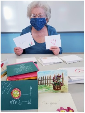 A woman with a face mask holding up greeting cards.