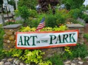 Art in the park sign in front of a garden.