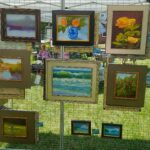 A display of framed paintings in a grassy area.