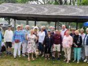 A group of older people posing in front of a pavilion.