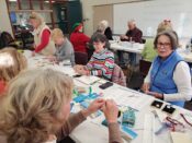 Group of people making crafts at a table.