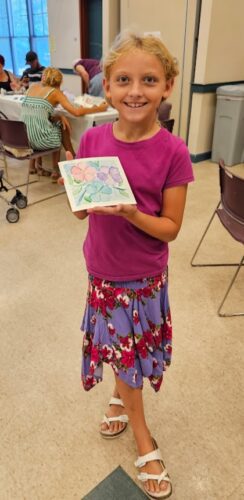 Girl holding watercolor painting of flowers.