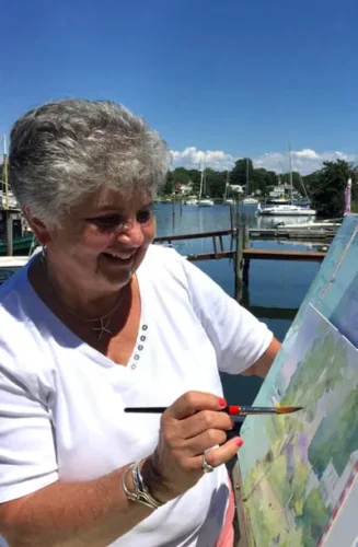 Woman painting outdoors with a brush.