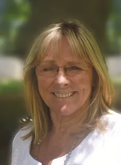 Smiling woman with glasses outdoors.
